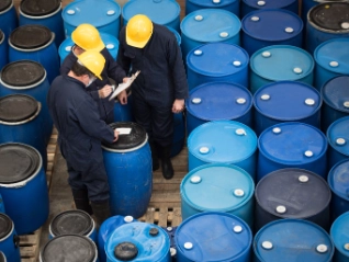 Three men inspecting chemical drums
