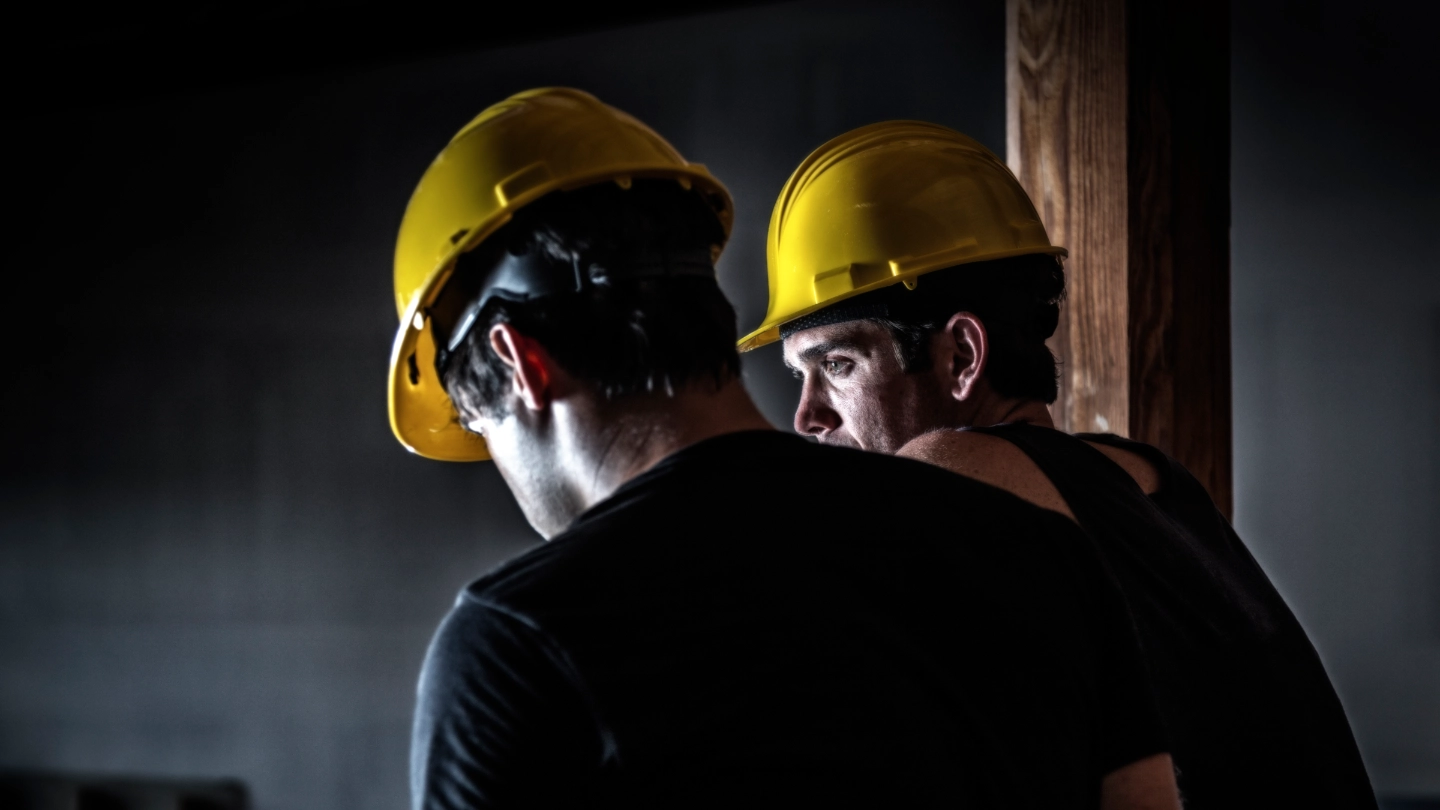 Two construction workers wearing yellow helmuts